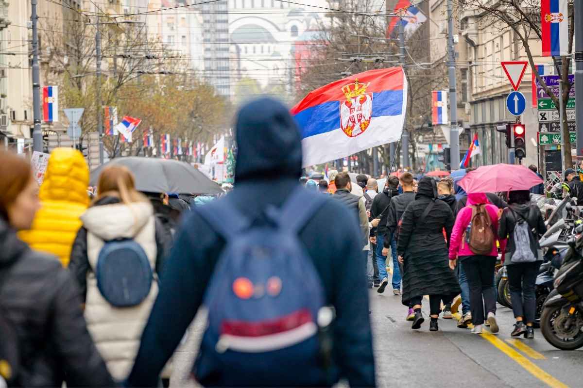 prikaz ljudi koji šetaju na ulicama sa srpskim zastavama